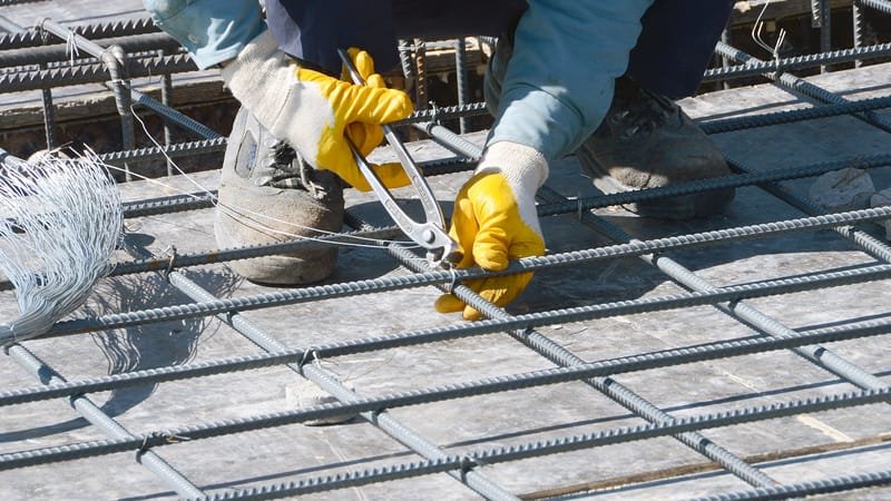 Ferrailleur ligaturant les armatures d'un plancher avant coulage